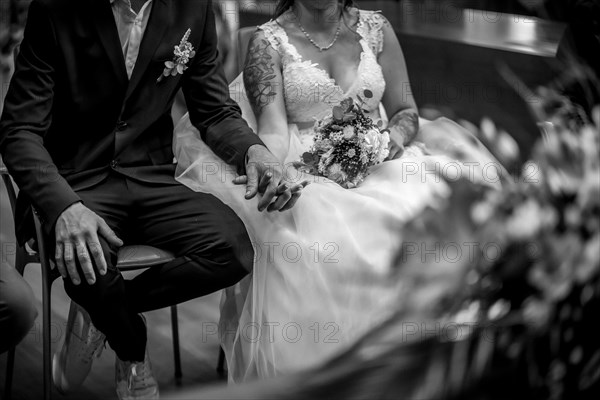 Bride and groom sitting at the ceremony holding hands at a wedding