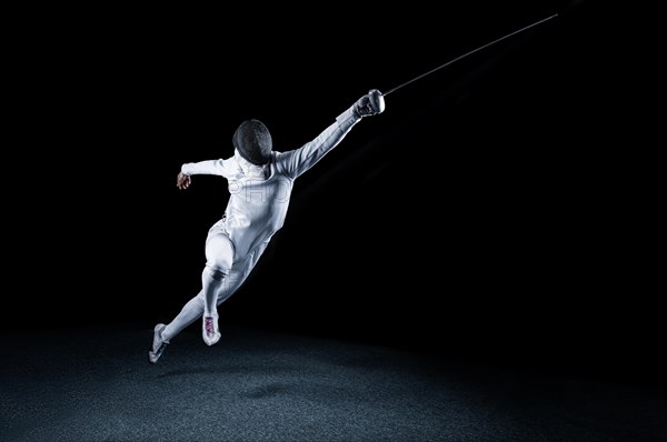 The fencer moves forward with a sword in his hand. Sport concept.