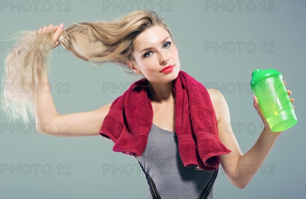 Charming model posing in the studio with a shaker in her hands and a towel around her neck.