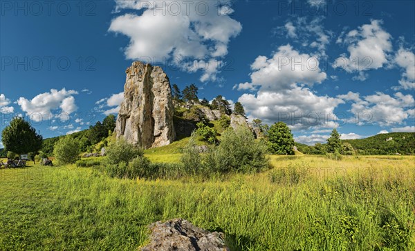 Striking limestone rock formation Burgstein with blue and white sky in the upper Altmuehltal surrounded by green vegetation