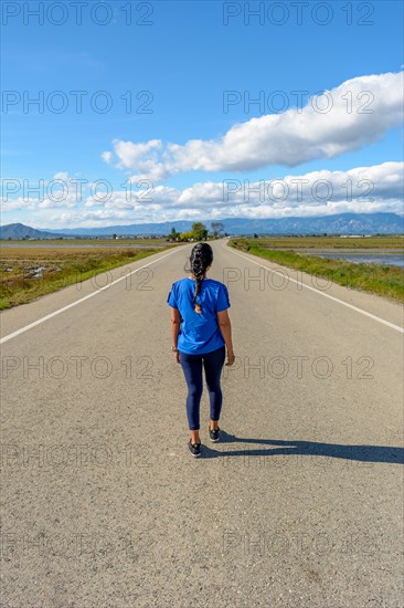 View from behind an individual walking along a deserted road with scenic views on a clear day