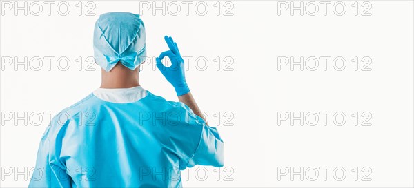 Portrait of a doctor on a white background. He shows an ok sign. The view from the back. Medicine concept.