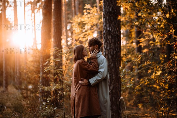 Beautiful fashionable couple in love in the forest at sunset in autumn