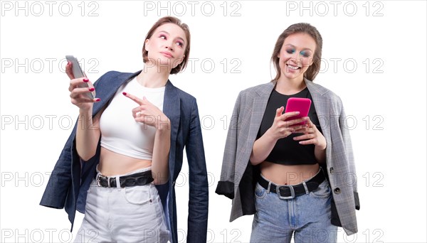 Two girlfriends are texting on their smartphones and laughing. Bloggers concept. Gossips.