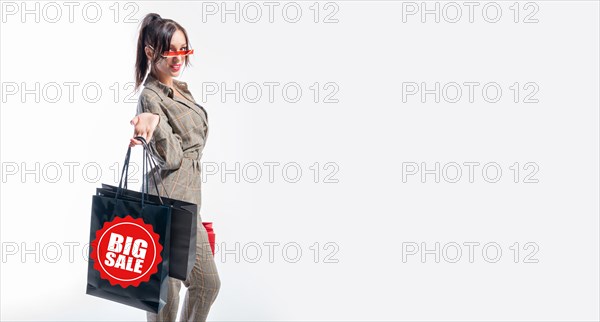Stylish girl in a suit with packages in her hands. Big sales. Holiday shopping concept.