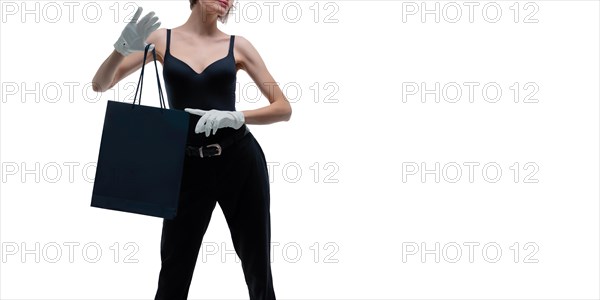 Beautiful young woman in white gloves holds a black craft bag in her hand. Shopaholics concept. Spenting. Gifts for the holidays. Black Friday. Shopping centers.