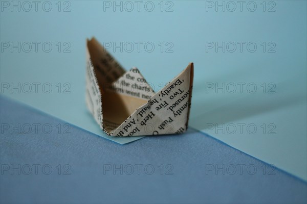 A paper boat in origami form against a contrasting blue background