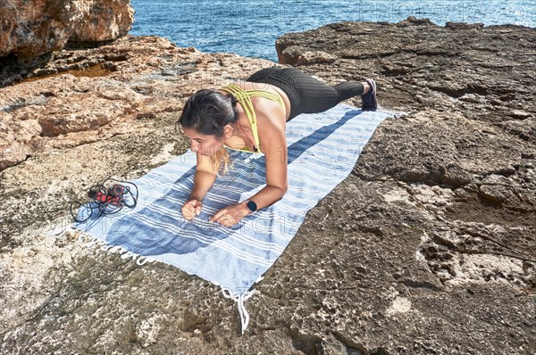 FITNESS WOMAN IN SPORTS SET TRAINING WITH ELASTIC BAND