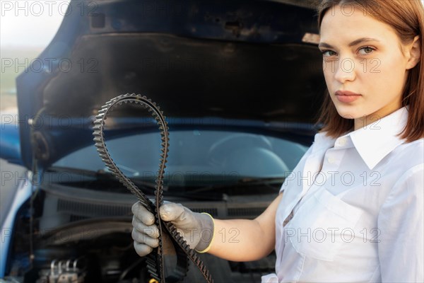 Young beautiful and hot woman auto mechanic holding a timing belt in her hands