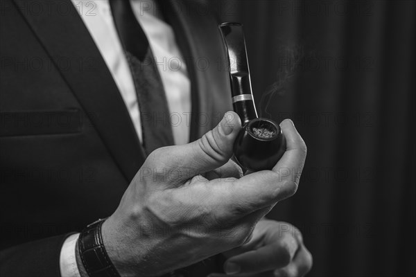 Image of male hands holding a smoking pipe. Tobacco smoking concept.