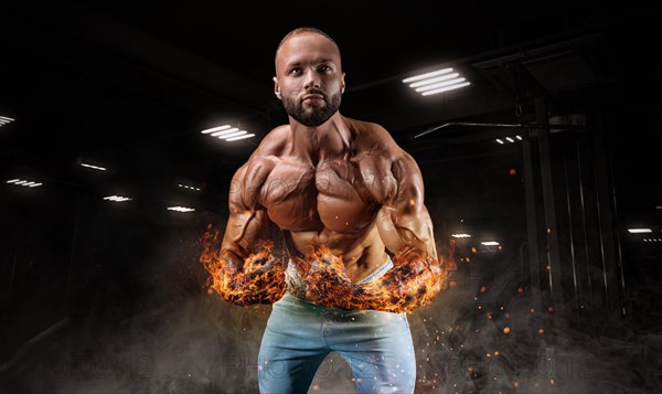 Professional athlete with fiery hands posing in the gym. Bodybuilding