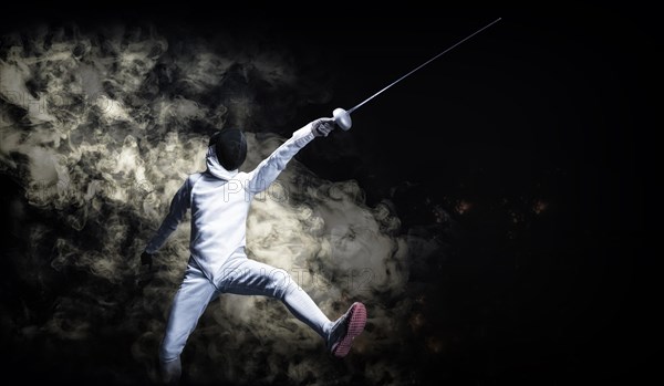 The fencer moves forward with a sword in his hand. Sport concept.