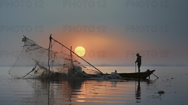 Fisherman attended to his net on a still water surface during a warm sunset