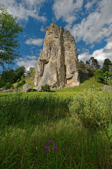 Striking limestone rock formation Burgstein with blue and white sky in the upper Altmuehltal surrounded by green vegetation