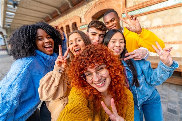 Young diverse friends gesturing success while taking a selfie in the city street