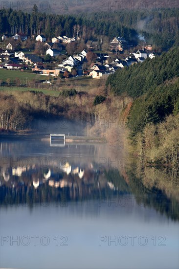 The Steinbach Dam near the national park community of Langweiler on the edge of the Hunsrueck-Hochwald National Park with fog on an early winter morning