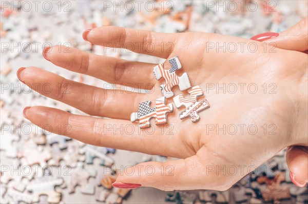 Woman sprawling three puzzles with the US flag on her hand. Economic and political concept.