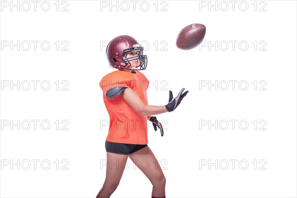 Woman in the uniform of an American football team player catches the ball. White background. Sports concept.