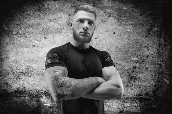 Young muscular guy posing against the background of a concrete wall. Fitness and nutrition concept.