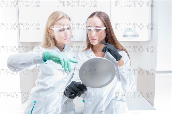 Two beauticians pose in a medical salon with a mirror in their hands. Rejuvenation concept.