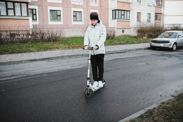 Young stylish guy rides an electric scooter around the city