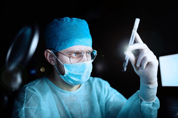 Scientist doctor in a dark laboratory with a test tube of a medicinal product