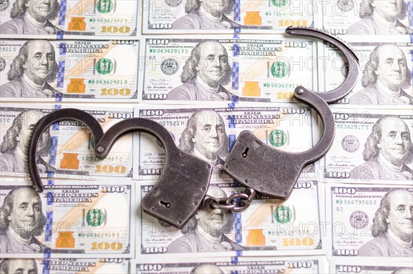 Handcuffs on the background of hundred-dollar bills. Illegal trade. Justice concept.