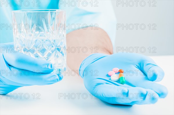 The doctor holds out pills and a glass of water. Medical concept.