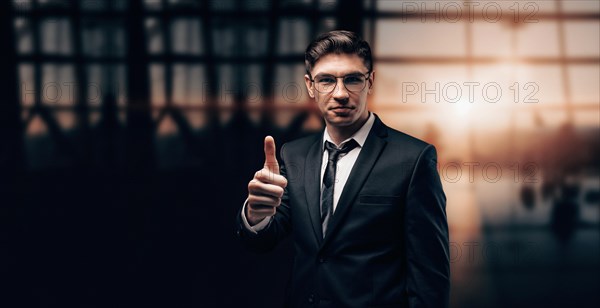 Portrait of a man in a business suit. He is standing at the airport with his finger raised. Ok sign. VIP transportation. Private airlines. Charter flights.