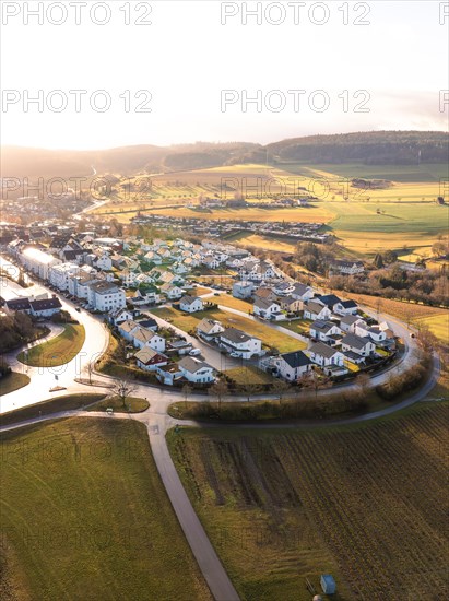 Aerial view of a village surrounded by fields during sunset