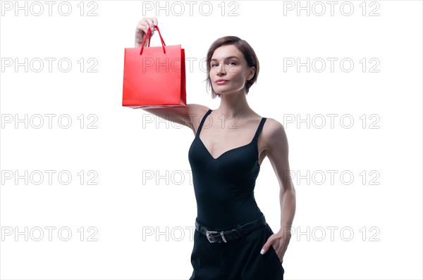 Beautiful young woman holding a craft red package in her hand. Shopaholics concept. Spenting. Gifts for the holidays. Black Friday. Shopping centers