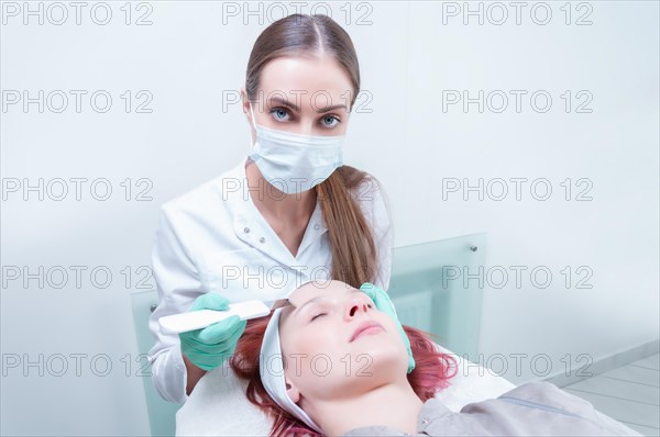 The beautician washes the patient's face before peeling. Skin care concept.