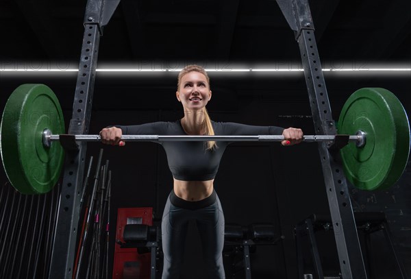 Beautiful tall blonde is doing push-ups from the bar in the gym. Fitness and bodybuilding concept.