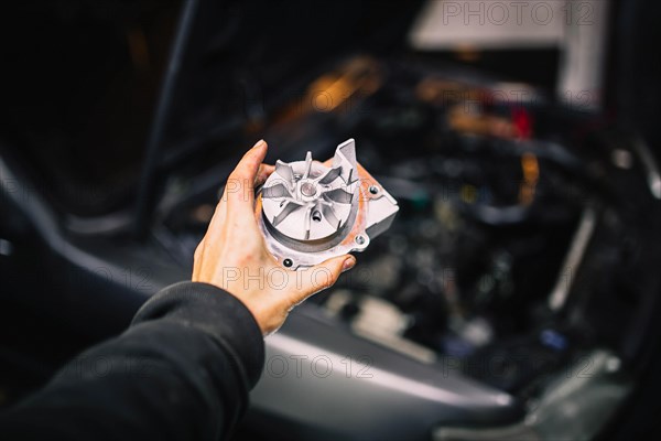 Automotive water pump of the engine cooling system in the hands of an auto mechanic