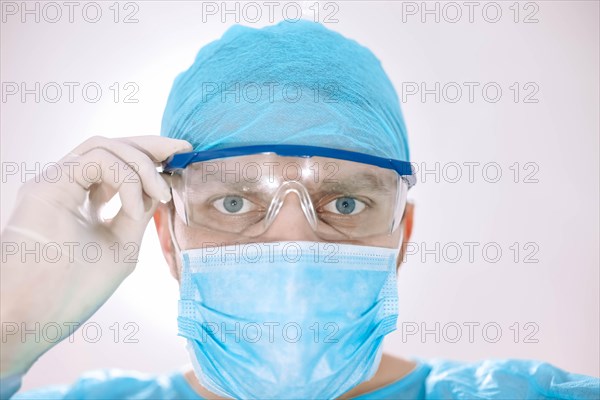 Male surgeon doctor in the operating room looking at the patient at the camera