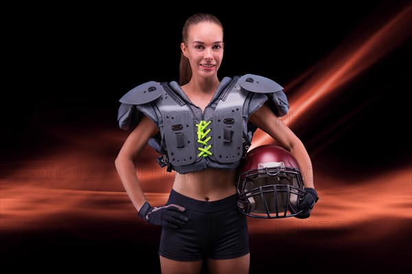 Portrait of a sportive girl in the uniform of an American football team player. Sports concept. Futuristic background.