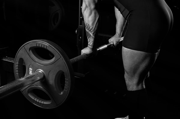 The athlete approaches the barbell and takes hold of it. Bottom view