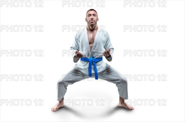 Athlete in a kimono with a blue belt stands in a fighting position. Concept of karate