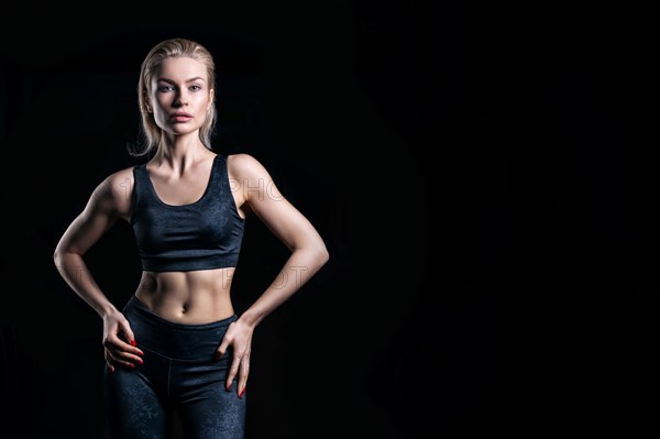 Charming sportswoman posing in the studio on a black background. The concept of bodybuilding
