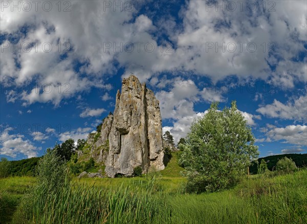 Striking limestone rock formation Burgstein with blue and white sky in the upper Altmuehltal surrounded by green vegetation