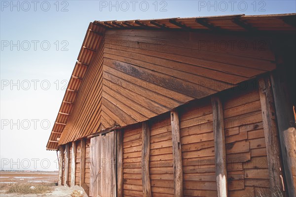 Side of a barn with wooden walls and a tin roof against the sky. Kampot