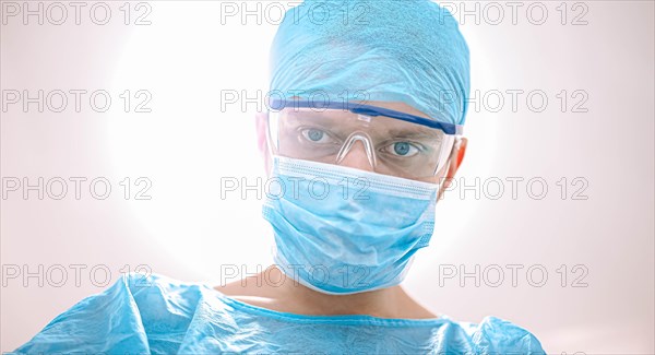 Male surgeon doctor in the operating room looking at the patient at the camera