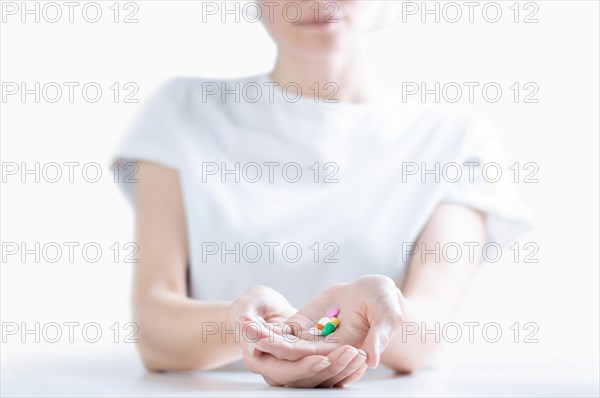 Woman in hospital clothes holds a set of pills in her palms. The concept of unstable psyche