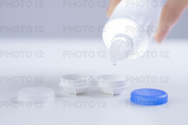 Liquid for lenses is poured into the boxes. Ophthalmology concept. White background.