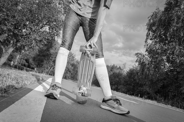 The girl holds a skateboard in her hands. Track in the park. Sports concept.