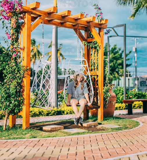 Portrait of a smiling girl sitting on a swing in La Calzada