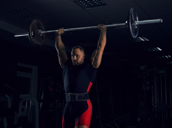 Weightlifter lifts the bar above his head. Strength training with a huge weight