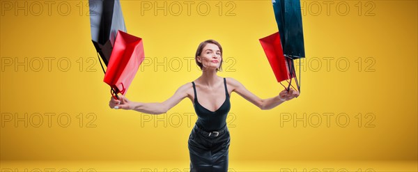 Cheerful positive girl jumps up with happiness and waving shopping bags. The concept of holiday gifts