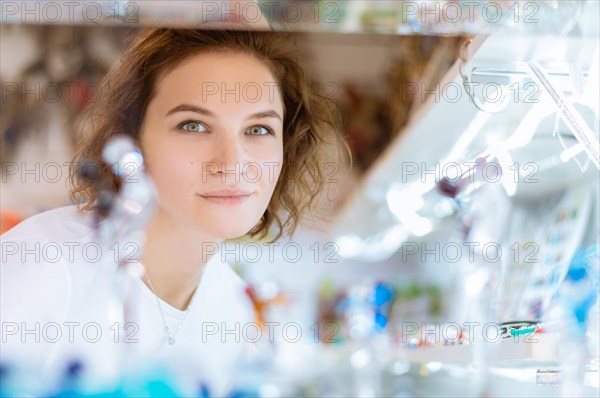 Portrait of a charming girl who looks at the camera from behind the window of a souvenir shop.