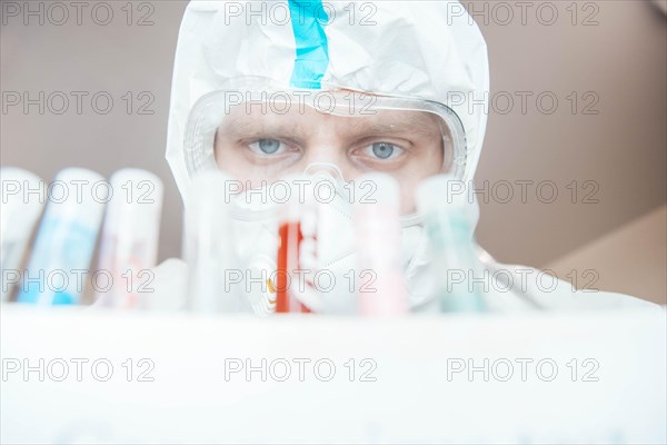 Medical scientist in uniform examines a test tube with blood in a laboratory